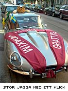 En Jaguar E-type, insvept i röda band med texten "Grattis Joakim Student 2003"